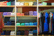 Various color sweatshirts at shelf and shirts on hangers in shop, Italy