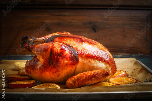 Fotografie, Obraz Roast whole turkey or chicken over wooden background, side view