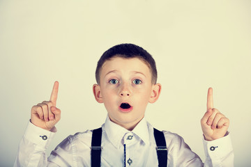 Wall Mural - Pointing up smiling  little boy isolated over white background.