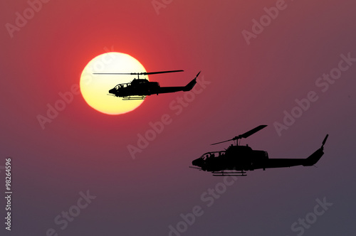 Obraz Dibond Dwa latającego helikoptera wojskowego na tle zachodu słońca