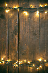 Holiday christmas rough wood background with lights garland.