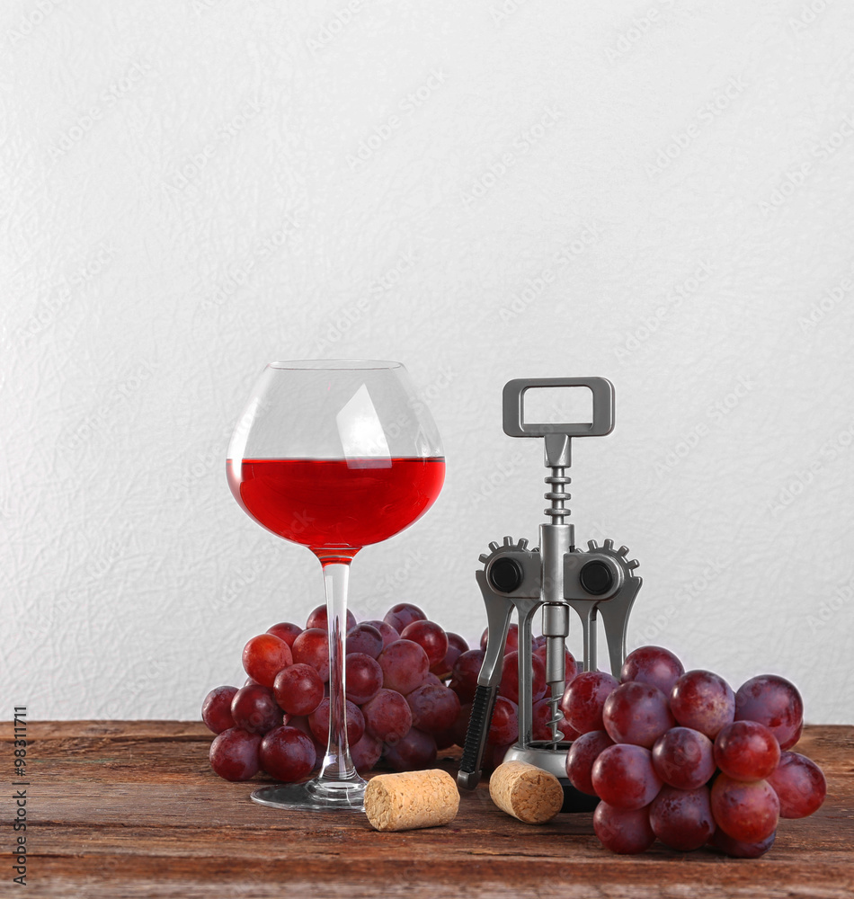 Wine and grape on wooden table against light background