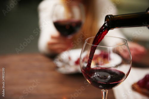 Fotografía Pouring red wine from bottle into the wineglass