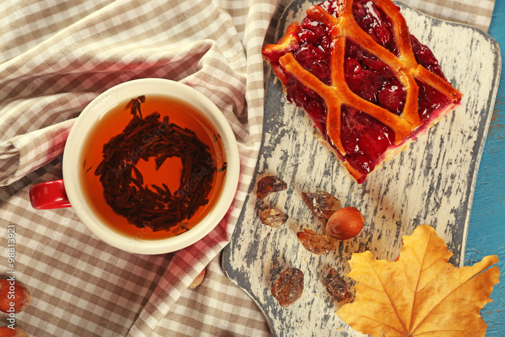 Cup of tea with autumn decor on wooden table.
