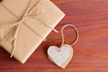 Gift box packed brown paper and twine with two cardboard hearts tied together top view on wooden table with space for text