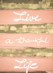 Concept image of Live a Thankful Life motivational quote hand written on vintage painted wooden wall