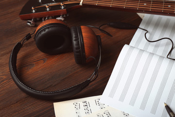 Wall Mural - Guitar with earphones and music sheets on wooden background