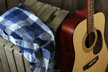 Wall Mural - Guitar and shirt left on crate on wooden wall background