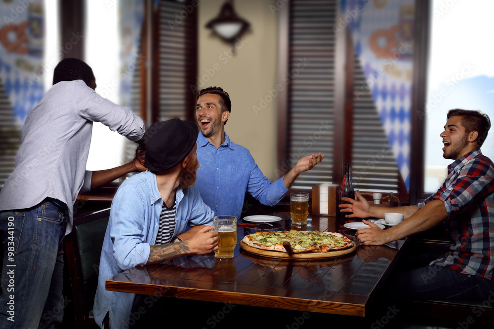 Young men drinking beer and talking in cafe