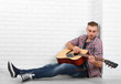 © Africa Studio - Young musician with guitar on light wall background