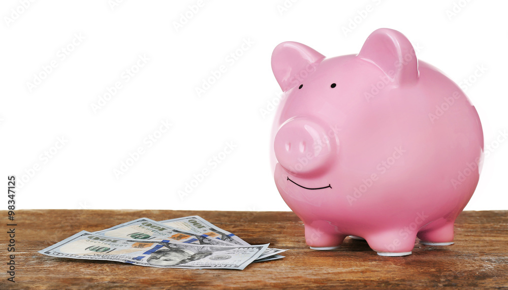 Piggy bank with banknotes on wooden table, isolated on white