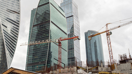 Tower cranes on construction site before skyscrapers
