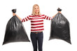 Cheerful woman holding two trash bags