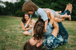 © sergiubirca - Happy young hipster family having fun while running, bowl,  rising up, piggyback ride their children in park on summer sunset
