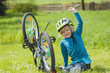 © Westend61 - Portrait of smiling little boy repairing bicycle on meadow