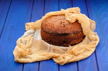 homemade chocolate fruit cake wrapped in chesecloth on blue tabl