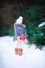 Wall Mural - Adorable little girl with christmas box gift in winter outdoors