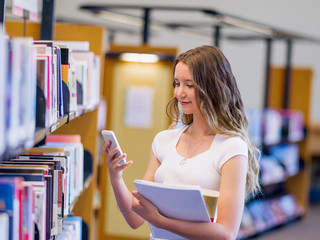 Wall Mural - Happy female student holding books at the library