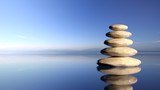 Fototapeta Desenie - Zen stones stack from large to small  in water with blue sky and peaceful landscape background.