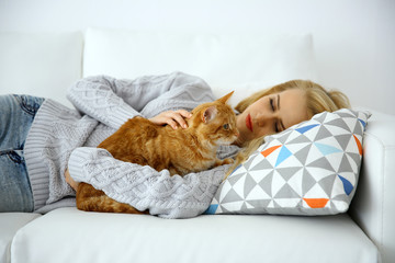 Wall Mural - Young woman with red cat laying on sofa