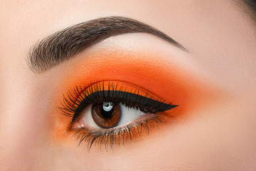 close-up of woman eye with beautiful orange smokey eyes