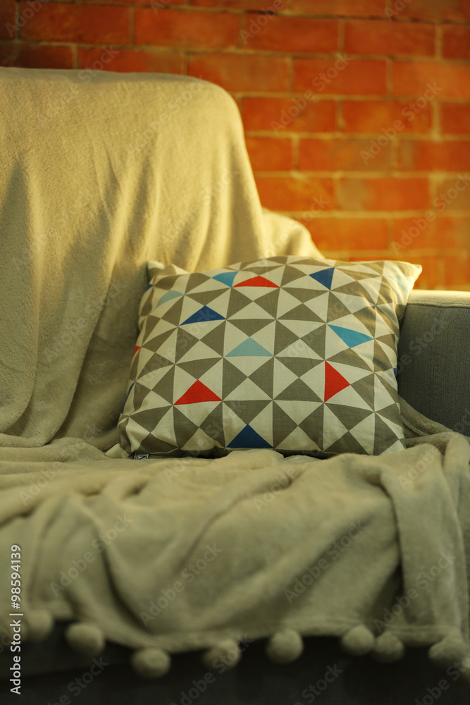 Comfortable sofa and modern lamp on brick wall background, close up
