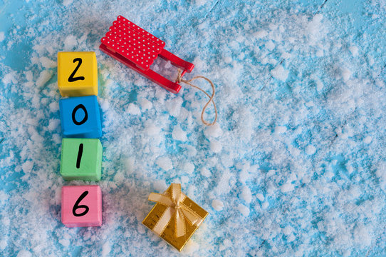 New 2016 Year wood number on color wooden cubes with snow, sled, gift and empty space for text. Happy new year concept postcard