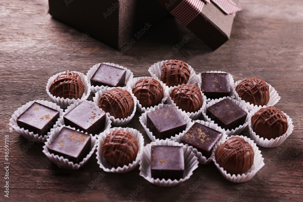 Assorted chocolate candies with gift box on wooden background