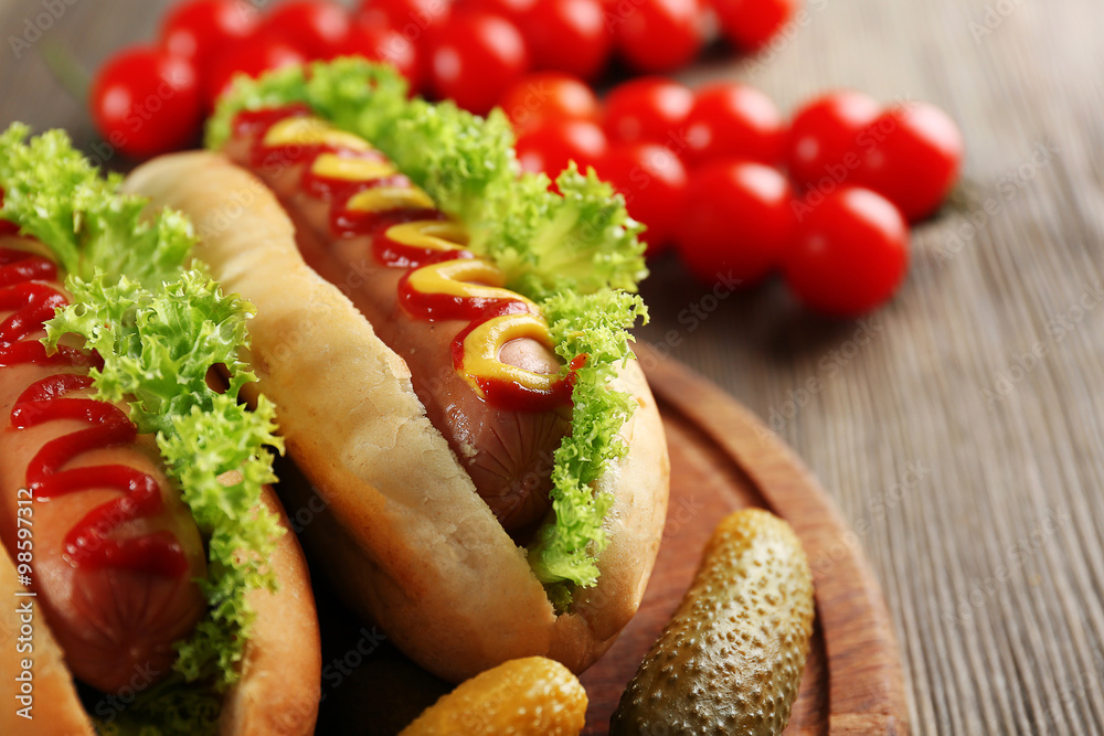 Tasty hot-dogs with vegetables on wooden table