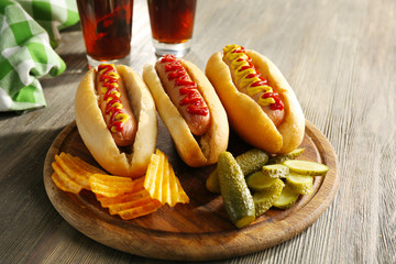 Canvas Print - Delicious hot-dogs with pickled cucumbers and chips on wooden chopping board