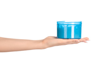 Wall Mural - Health and body care topic: a woman's hand holding a blue jar with cream isolated on white background