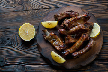 Canvas Print - Baked pork ribs served with lemon on a wooden chopping board