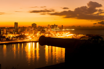 Wall Mural - Sunset in Havana with a view of  the city skyline and an old spanish cannon