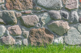 Fototapeta Lawenda - Wall made of irregular granite stones with green grass