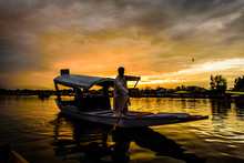 The Silhouette Of A Boat Glides Along The Surface Of Dal Lake Du