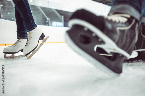 Fototapeta na szkło Man's hockey skates and women's figure skates on ice background