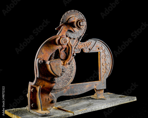 Fotografie, Obraz Antique very rusty meat slicer on rustic barn wood against a black background