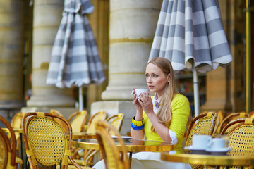 Young romantic Parisian girl in an outdoor cafe using tablet