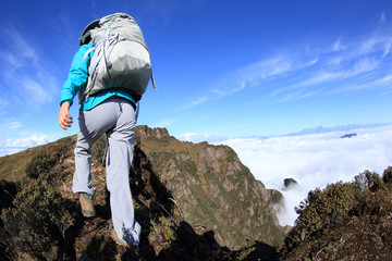 young woman backpacker hiking at beautiful mountain peak