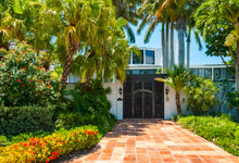Architectural Building In Florida Entrance Door Of Tropical Luxury Villa. Palm Trees In Front Of Beautiful Mansion With Terracotta Floor Tiles On Sunny Day In Summer
