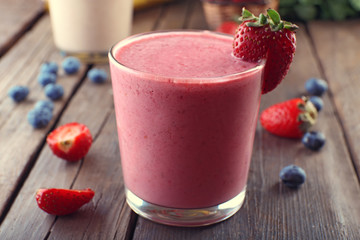 Wall Mural - Glasses of fresh cold smoothie with fruit and berries, on wooden background