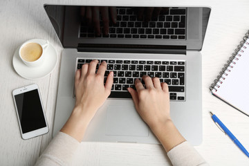 Wall Mural - Woman working with laptop placed on wooden desk. Top view