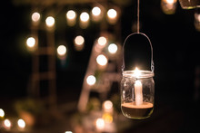 The Lamp Made Of A Jar With A Candle  Is  Hanging  On A Tree At Night. Wedding Night Decor. Night Ceremony