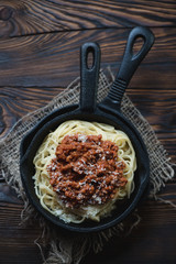 Wall Mural - Frying pan with spaghetti bolognese and cheese, above view