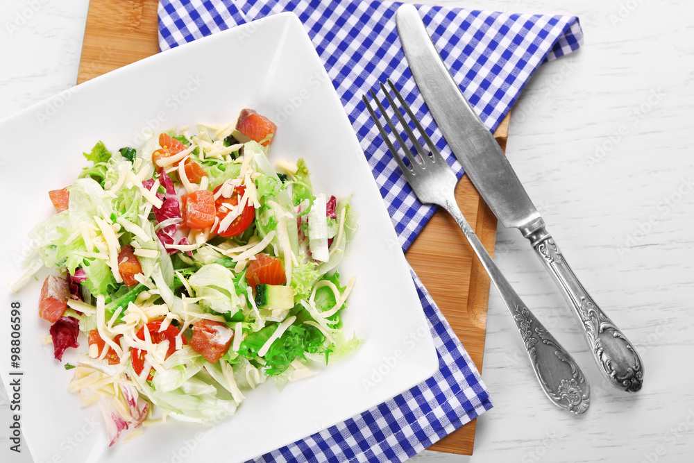 Tasty salmon salad on wooden table background