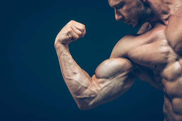 The athlete shows his beautiful body on black background.