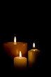 Three burning candles isolated on black background. 
