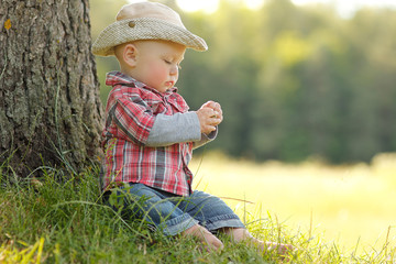 little boy playing in a cowboy hat on nature