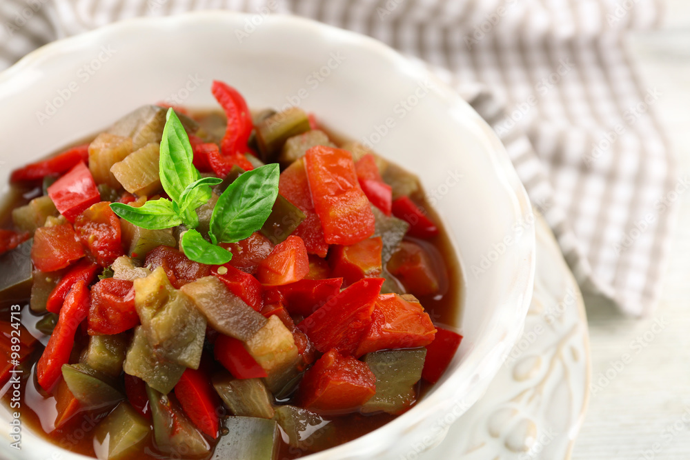Ratatouille in bowl, on wooden table background