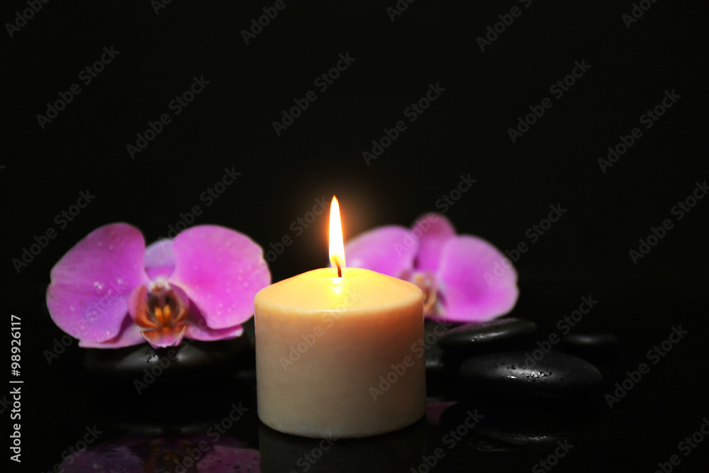 Composition of orchid, pebbles and candle on dark background